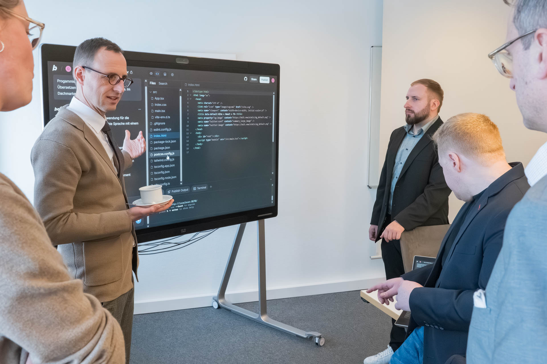 Ein Mann zeigt vor anderen Personen auf einen smarten Beamerbildschirm